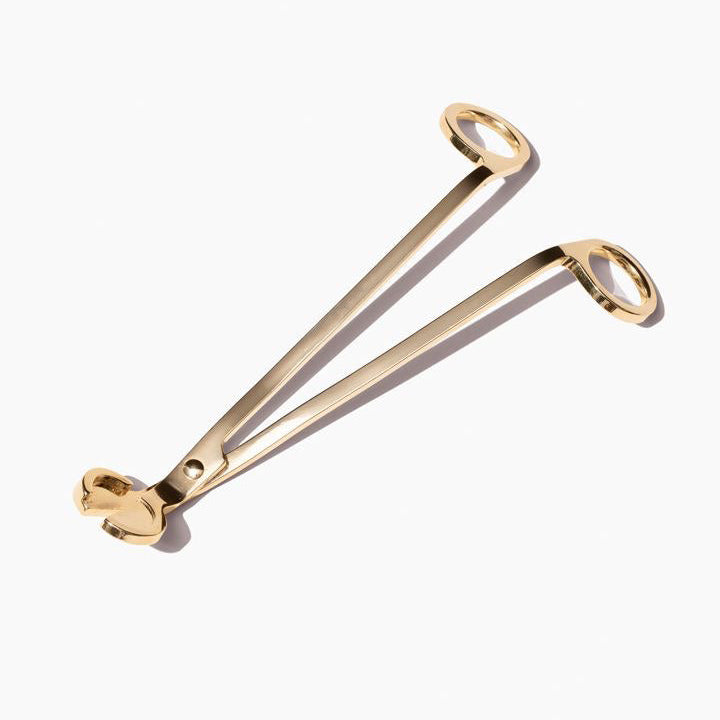 Gold-colored wick trimmer on a white background